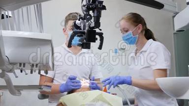专家、助手使用<strong>光学显微镜</strong>对牙科室躺卧病人口腔进行手术。
